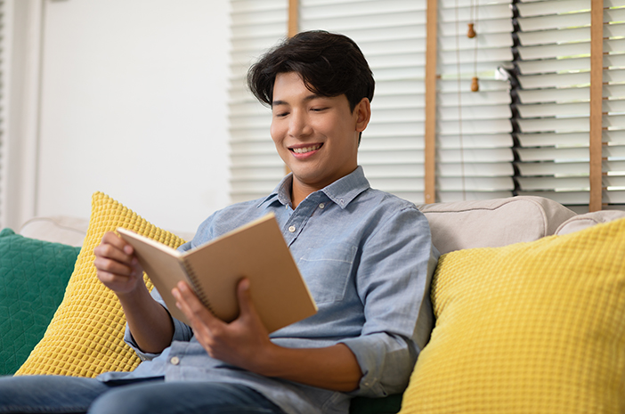 Happy,handsome,asian,man,sit,on,couch,smile,and,reading